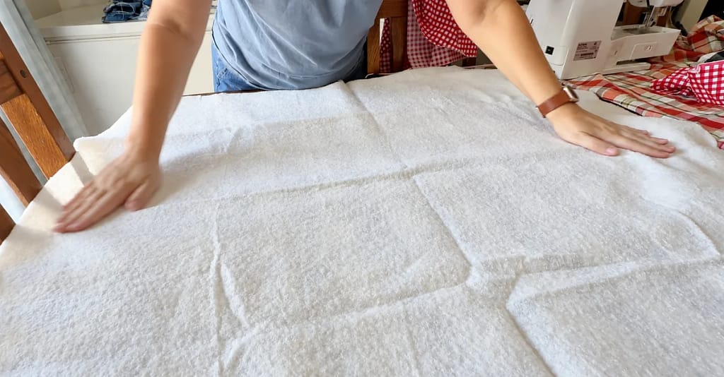 Cotton batting spread over the quilt backing on a table.