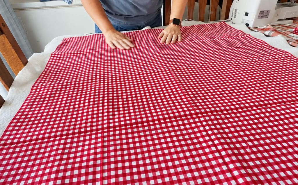 Red gingham smoothed over batting to make the quilt sandwich.