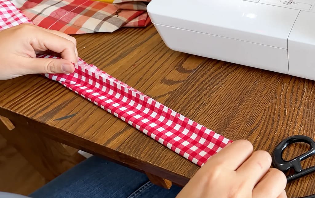Red gingham handle strip folded lengthwise to mark the center.