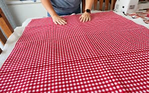 Red gingham smoothed over batting to make the quilt sandwich.