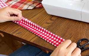 Red gingham handle strip folded lengthwise to mark the center.