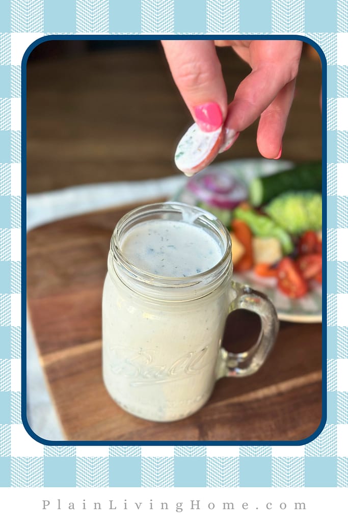 dipping a fresh sliced tomato into a jar of the best homemade ranch