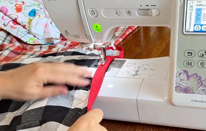 Close view of the red binding being sewn to the quilt.
