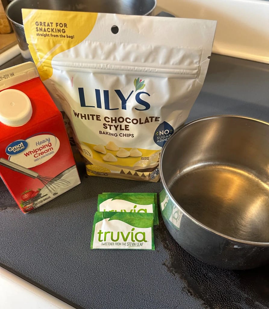 Lily’s white chocolate-style chips, heavy cream, and Truvia beside a saucepan