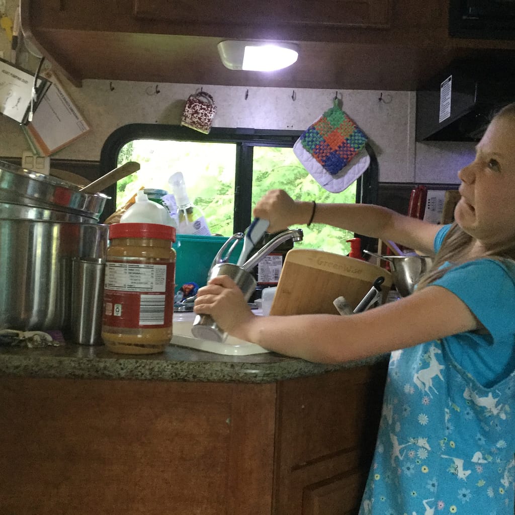 Maddy washing dishes in the camper