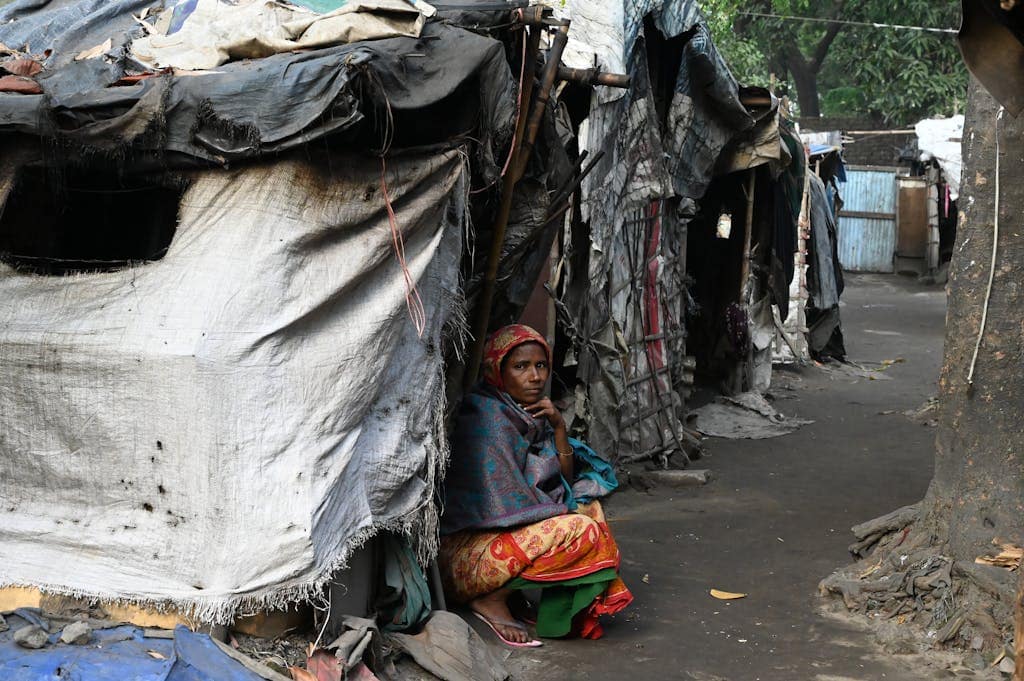 A woman sits outside a temporary shelter in a slum area of Chittagong, Bangladesh.