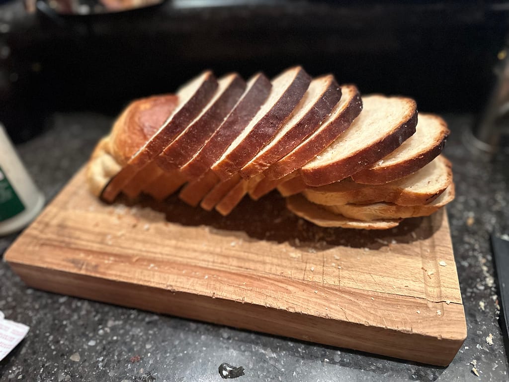 slices homemade bread stacked on a wooden cutting board