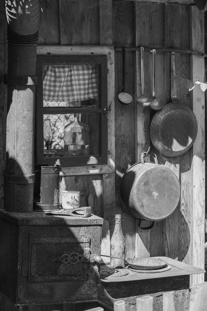 A rustic kitchen scene featuring vintage cookware and a wood stove, pots and pans