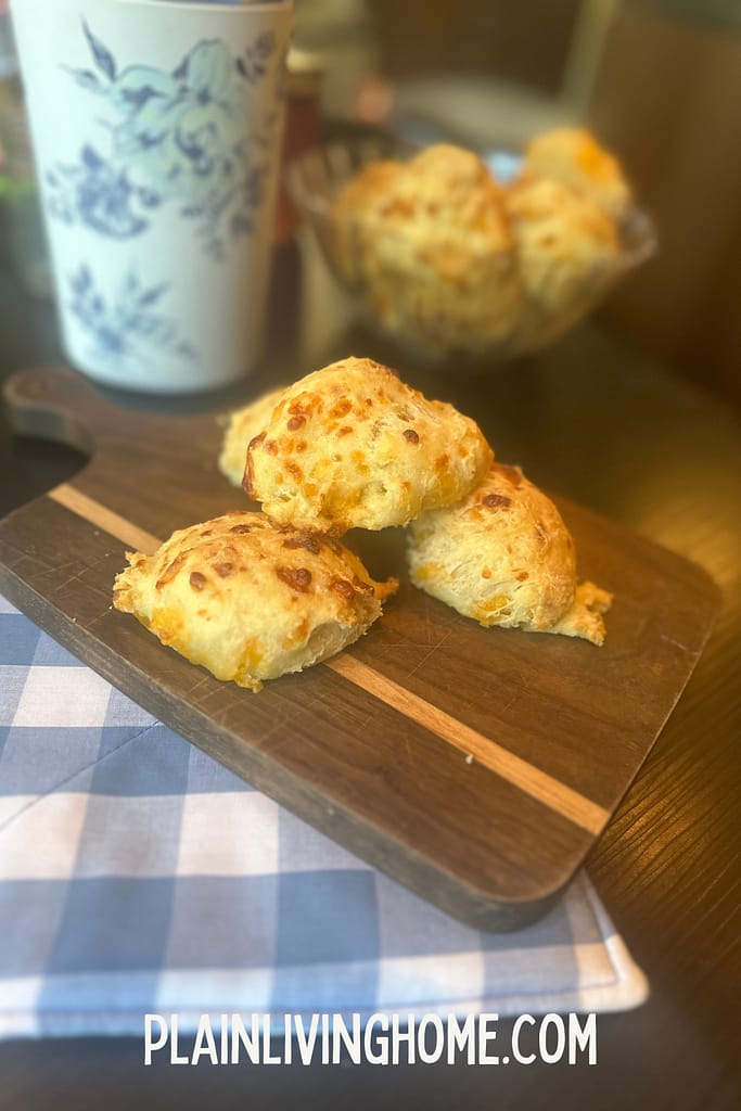 sourdough cheddar biscuits stacked on a wooden cutting board