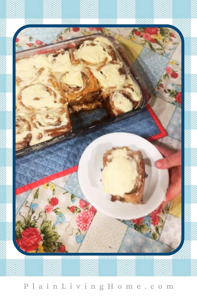 serving a warm cinnamon roll with buttercream icing dripping over the edges