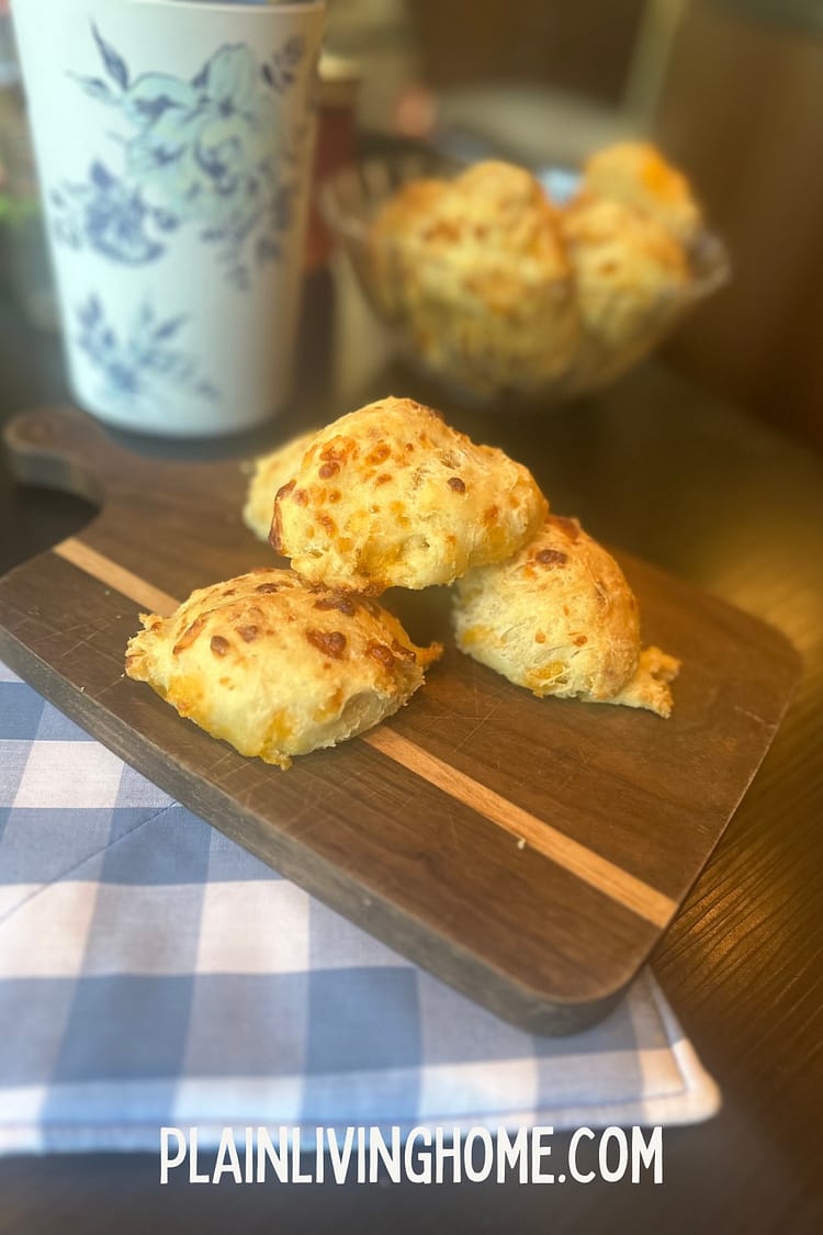 sourdough cheddar biscuits stacked on a wooden cutting board